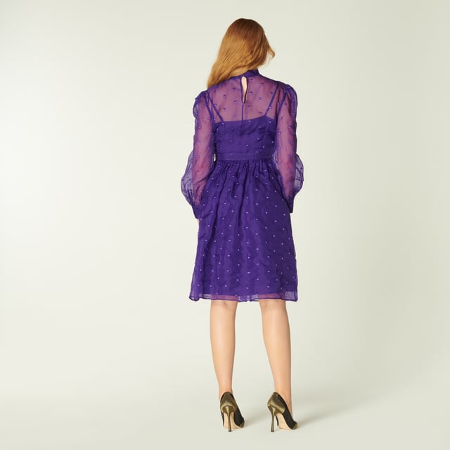 A vibrant play on our vintage-inspired Glinda pieces, Depp takes on the spotty organza in striking violet. Crafted from fine silk organza in purple dotted with purple embroidered spots, this long-sleeve dress has a round neck finished with an oversized bow, a slip layer, a nipped waist and a full skirt. Wear it with sharp courts and a clutch when those dressing up moments call.