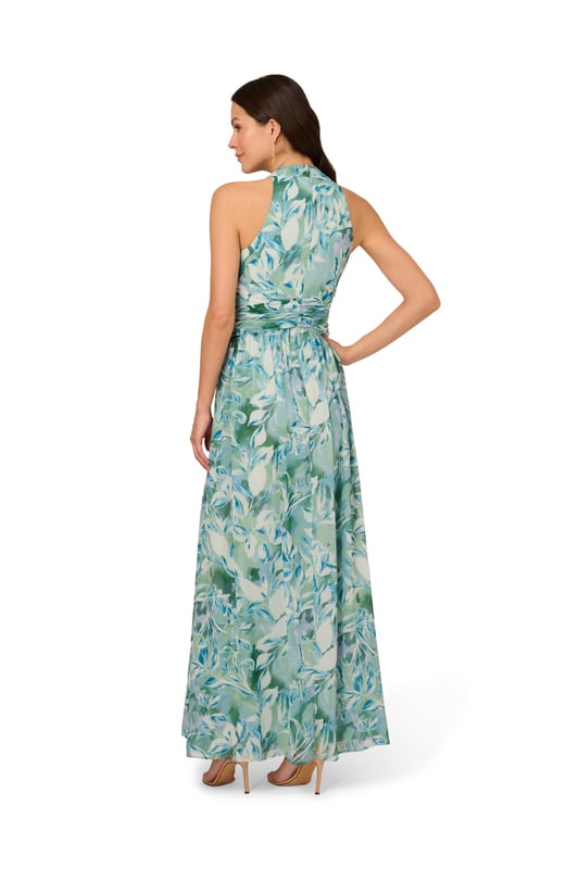 Pretty little details make this halter gown shine. This formal dress features a faux wrap bodice with halter neckline, shirred detailing at the waist surrounding a fabric-trimmed ring at the centre, and a flowing skirt with thigh-high slit. Fully lined, this dress is crafted from leaf-printed chiffon with shirred detailing through the skirt. A zipper closure at the centre back completes this evening gown. A pretty look for day or nighttime events, style this dress with nude heels and a sparkling clutch.