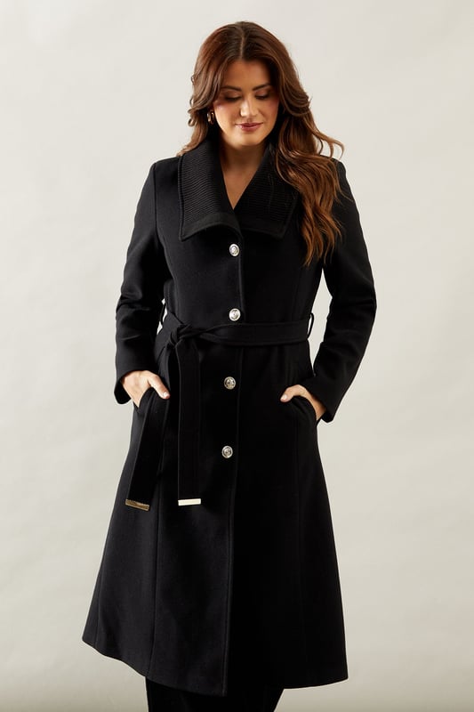 Elegant knitted collar for added sophistication
        Wrap design with button-through closure for versatile styling
        Long length offers maximum coverage and warmth
        Belted waist creates a flattering silhouette
        Functional side pockets for practicality
    
    This Wallis Knitted Collar Button Through Wrap Coat is the epitome of refined elegance. Perfect for the woman who appreciates sophistication without compromising on comfort, this coat is a versatile addition to any wardrobe. The wrap design allows for customisable fit, while the button-through closure adds a touch of classic charm. Style it over a sleek midi dress and pair with heeled boots for a polished look at formal events. For smart casual occasions, layer it over tailored trousers and a fine knit jumper, completing the ensemble with leather ankle boots. The long length and belted waist not only provide warmth but also create a striking silhouette that's sure to turn heads. Whether you're attending a business meeting or heading to a sophisticated dinner, this coat will ensure you look impeccably put-together while feeling effortlessly comfortable.