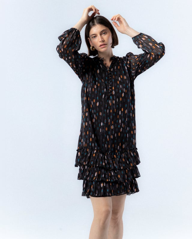 El vestido de lunares Alejandra, con su encantador estampado de lunares en tonos cálidos sobre fondo oscuro, te hará sentir la magia del otoño. Su diseño elegante y favorecedor es ideal para cualquier evento, añadiendo un toque de sofisticación y alegría a tu look.
 
 
 
 Vestido corto. 
 
 Abertura en escote con cierre de botones hasta la cintura. 
 
 Botones con aplique de piedras a mano. 
 
 Manga larga con puño elástico. 
 
 Bajo de tres volantes. 
 
 Tejido viscosa. 
 
 Estampado lunares.