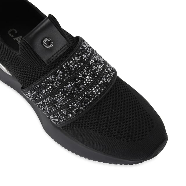 The Carvela Flare Sparkle trainer is a slip-on style with a black knitted upper. There is a crystal encrusted black fabric strap across the foot. The sole is chunky in black.