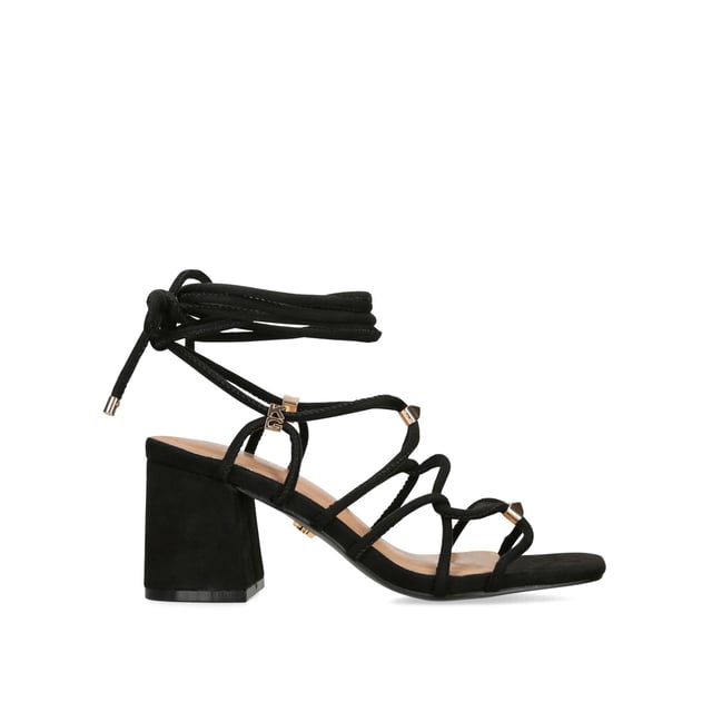 The KG Kurt Geiger Raya heel features a black microsuede upper with gold and KG Kurt Geiger stud hoops connecting the straps. The heel is a classic high block style. Heel height: 70mm.