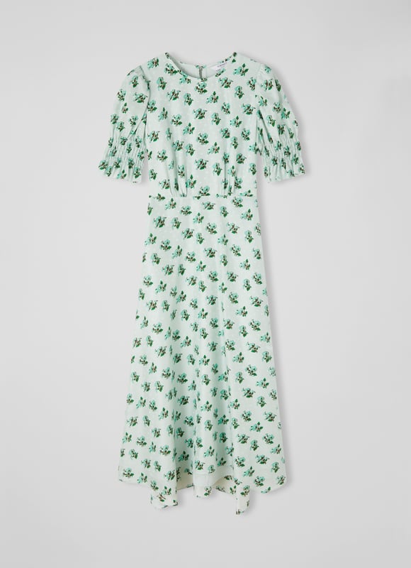 The Tabitha dress is crafted from a silk-blend spot jacquard in morning mist green with a 1930's hand painted primula print reimagined from vintage archives. It has a round neck, puff shoulders, short shirred sleeves, pleating at the bust, a floaty shape and a dipped midi-length hem.