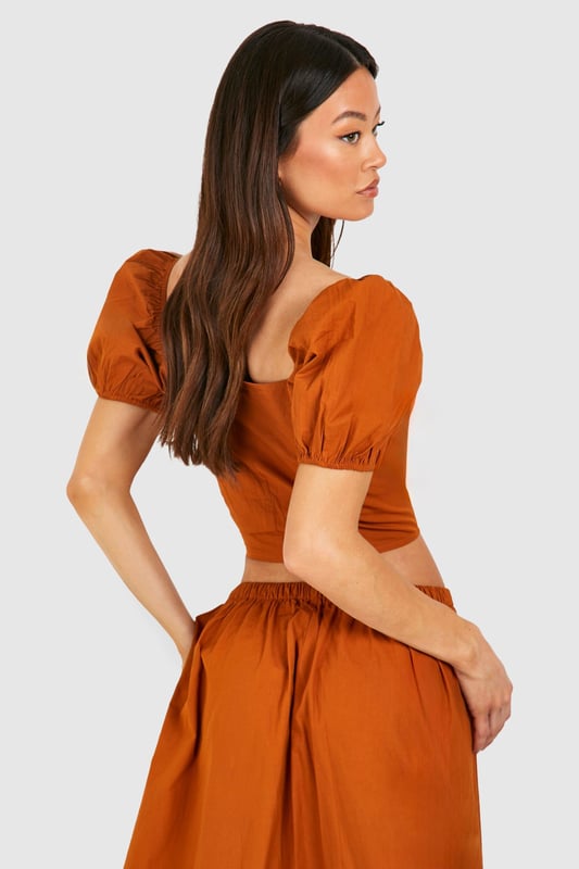 Plunging square neckline for a daring look
        Puff sleeves add a romantic touch
        Button-down front detail for adjustable styling
        Cropped length to showcase your midriff
        Fitted waist creates a flattering silhouette
    
    Make a statement in this eye-catching crop top that combines vintage charm with modern flair. The plunging neckline and puff sleeves create a captivating contrast, perfect for those looking to turn heads on a night out. Pair it with the matching high-waisted skirt for a coordinated ensemble that's sure to impress at your next social gathering. For a more casual look, team it with high-waisted jeans and trainers. The versatile design allows for easy transition from day to night - simply swap your footwear and add some bold jewellery to elevate your outfit for evening drinks or dancing. This Boohoo piece is ideal for the fashion-forward woman who isn't afraid to showcase her style and confidence.