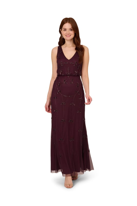 Put a little sparkle on display when you rock this sleeveless blouson gown. This formal dress features a sleeveless blouson bodice, deep v-neckline and back, and a soft skirt. Crafted with a luxe mesh fabric that is fully lined, this evening gown is embellished with sequin and beaded vines. The neckline and armholes of this gown are trimmed in beading for added sparkle. A hidden zipper closure at the centre back completes the design. This sleeveless beaded gown is a stunning look for a wedding guest or bridal party and pairs well with neutral or metallic accessories.