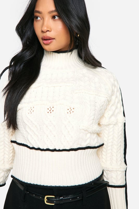 High neck design for a chic, sophisticated look
        Intricate cable knit pattern adds texture and visual interest
        Contrasting trim detail along sleeves and body for a striking effect
        Cropped length perfect for pairing with high-waisted bottoms
        Petite fit tailored for smaller frames
    
    Make a statement in this eye-catching petite cable knit jumper. The high neck design and contrasting trim details create a bold, contemporary look that's perfect for the fashion-forward woman. Style this versatile piece for a range of casual occasions, from coffee dates to family gatherings. Pair it with a high-waisted mini skirt and chunky loafers for a trendy daytime ensemble, or dress it up with tailored trousers and ankle boots for a smart-casual evening look. The cropped length is ideal for showing off your favourite bottoms, while the petite fit ensures a flattering silhouette for smaller frames. Add a leather jacket for extra edge, or keep it simple with minimalist accessories to let the jumper's unique design shine. This Boohoo piece is a must-have addition to your autumn-winter wardrobe, offering both style and comfort for the fashion-conscious woman.
