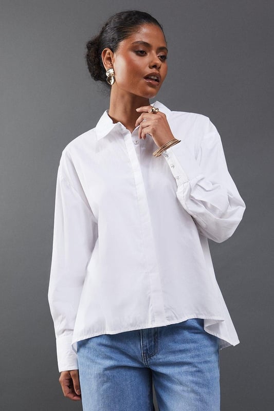 Striking open back design with tie detail
        Classic collared neckline for a polished look
        Long sleeves with button cuffs for versatility
        Relaxed fit through the body for comfort
        Crafted from breathable cotton poplin fabric
    
    Make a statement with this eye-catching poplin shirt from Warehouse. The open back design with delicate tie detail adds an unexpected twist to a classic silhouette, perfect for those who want to inject a bit of edge into their wardrobe. The relaxed fit and breathable cotton fabric ensure all-day comfort, while the collared neckline maintains a smart appearance. Style this versatile piece with your favourite denim for a casual daytime look, or dress it up with tailored trousers for a chic ensemble suitable for family gatherings or brunch with friends. The long sleeves can be rolled up for a more relaxed vibe, making this shirt adaptable for various occasions. Pair with flat sandals or trainers to complete your effortlessly cool outfit.