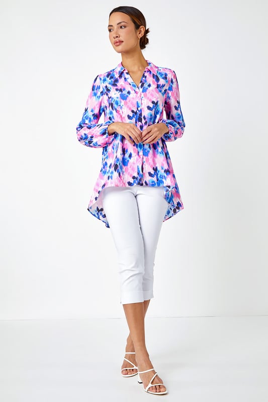 Abstract Print Dropped Hem Blouse from Roman. This sophisticated dropped hem blouse is cut from a smooth woven fabric and adorned in a colourful abstract print. It features a fully open front complete with button fastenings, full length cuffed sleeves and a smart collared neckline. A flattering dropped hem provides extra coverage at the back. Pair with cropped stretch trousers and heels for an evening out or add smart trousers and courts for work wear chic!