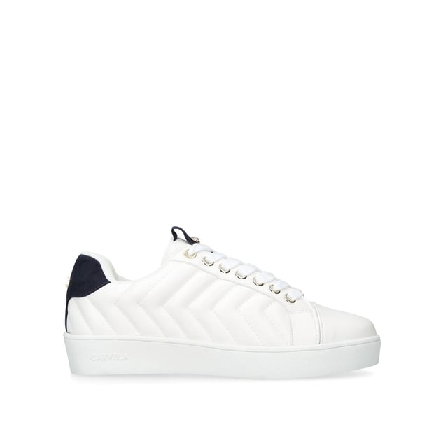 The Joyful Quilt is a white trainer with chevron quilt pattern on the exterior. The front is laced up with gold tone eyelets. The tongue features crystal stud. Gold tone Icon C stud at the back of the ankle.