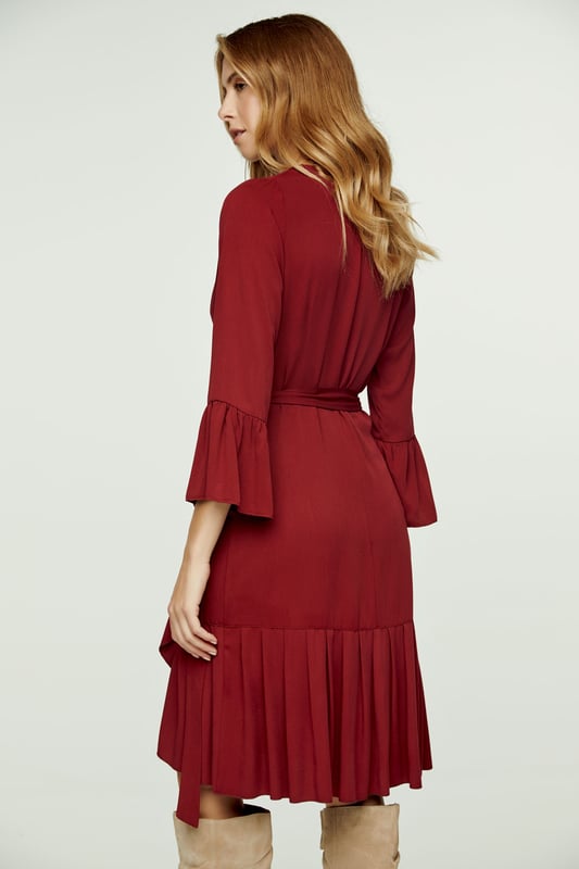 Deze wijndress is vervaardigd uit geweven viscose. Het heeft een V-hals en 3/4 klokmouwen. Deze wikkeljurk heeft een strik aan de linkerkant die door een gat aan de rechterkant wordt geregen en vastgebonden wordt met de strik aan de rechterkant opzij of op de rug. Er is een ruche langs de zoom van ongeveer 15 cm. De maten voor maat 36/S (in cm) zijn: Schouderbreedte-33, Buste-42, Taille-42, Zoom-70, Mouwlengte -Lichaamslengte-95/100. 100% viscose