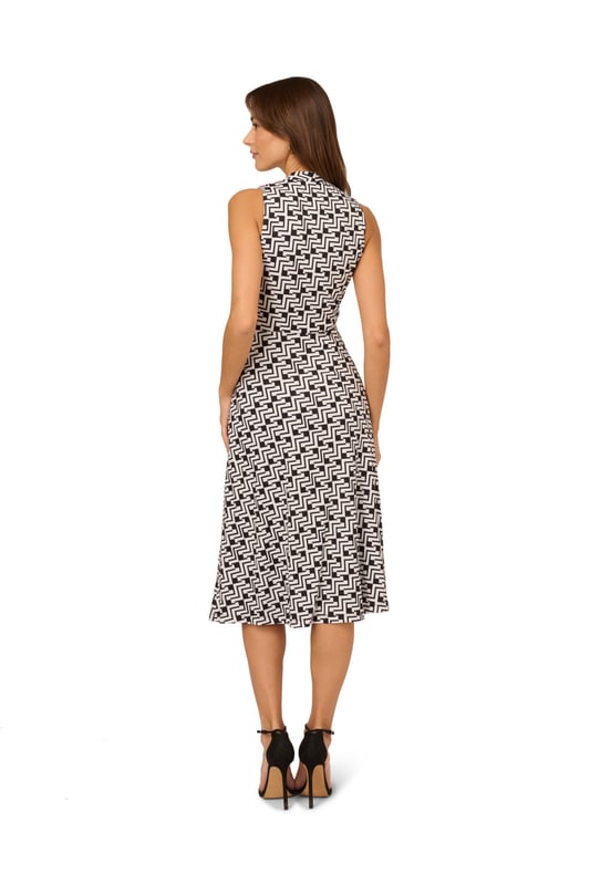 Great for work and for play, this sleeveless dress is a timeless look. This midi dress features a fitted bodice with a v-neckline, a knotted detail at the centre of the waist, and a soft skirt. Crafted from jersey fabric with comfortable stretch, this pull-on day dress boasts a geometric print. Styled with a blazer at the office, this sleeveless dress will take you all the way through happy hour.