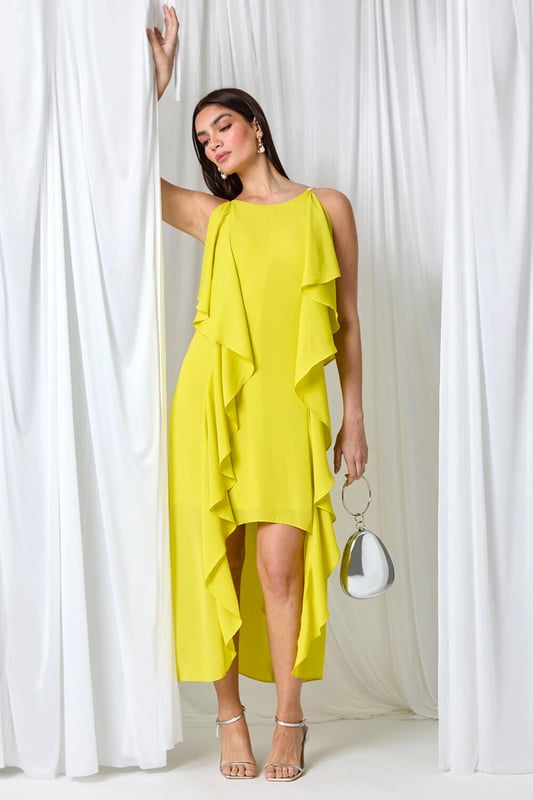 Plain Dipped Hem Ruffle Detail Midi Dress from Roman. Elevate your Summer wardrobe with this striking ruffle detail midi dress from the Ariella range. Featuring a elegant, cascading waterfall ruffle detail, this dress has a striking hi-low silhouette to add a touch of drama to your occasionwear. This sleeveless dress with a concealed back zip fastening is crafted from plain woven fabric and fully lined for maximum comfort. The metal trim on the shoulder straps provides a sophisticated edge. Whether you're attending a wedding or a formal dinner, style it with strappy heels and a clutch bag for event-ready glamour!
