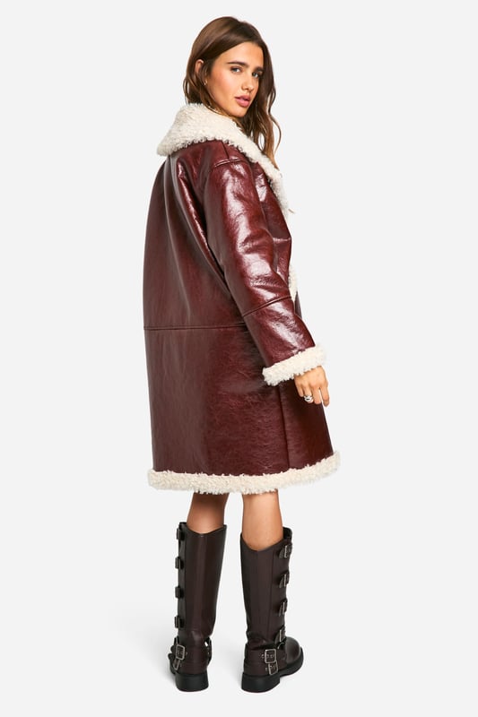 Long-line aviator style jacket with contrasting teddy lining
        Oversized notched collar for dramatic flair
        Plush faux fur trim along edges and cuffs
        Side pockets for practicality and warmth
        Durable PU outer for a leather-like appearance
    
    Make a bold statement this season with our striking long-line aviator jacket. This eye-catching piece combines the rugged charm of a classic flight jacket with the cosy comfort of teddy lining, perfect for braving the British chill in style. The oversized collar and plush trim add a touch of drama to your ensemble, while the durable PU outer ensures longevity. Style it as seen with a mini dress and chunky boots for an edgy, street-smart look that's ideal for casual outings or laid-back gatherings. Alternatively, layer it over jeans and a jumper for a more relaxed weekend vibe. This versatile jacket effortlessly bridges the gap between fashion-forward and functional, making it a must-have addition to your autumn/winter wardrobe.