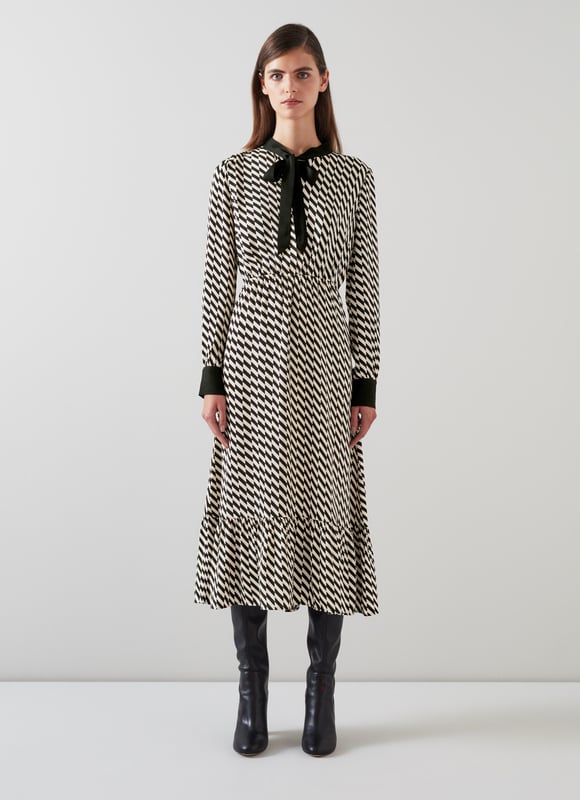 Effortless sophistication with the Bridget graphic print dress in timeless black. This smart casual piece, crafted from high-quality viscose, features a geometric design, adjustable neck tie, and convenient pull-on style. Perfectly pairs with sleek boots or classic heels for a refined look.