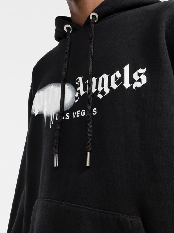 Palm Angels reemplaza su logotipo cl�sico con esta versi�n de Las Vegas, realzada con un efecto de pintura en aerosol en color blanco sobre un fondo negro s�lido. Confeccionada con algod�n suave, esta selecci�n SS22 tiene un corte relajado que encarna la est�tica de la marca y se completa con un pr�ctico bolsillo canguro en el centro.