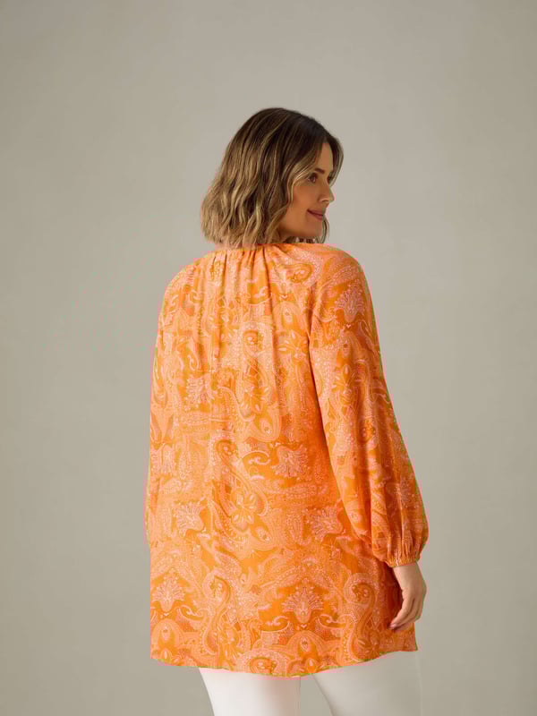 In a pretty orange paisley, this tunic is cut from a soft woven fabric thats so comfortable to wear. With a lengthening V-neckline, it has a bust seam and full-length elasticated sleeves which create a stylish silhouette. Its long, tunic length adds to its flattering feel, making it the perfect everyday piece.
