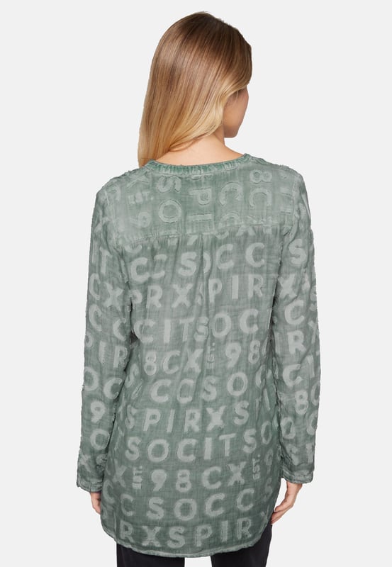 Deze blouse voor dames is een veelzijdige basic. Het heeft een losse pasvorm en is gemaakt van hoogwaardige materialen. De tuniekhals eindigt in een doorlopende knoopsluiting. De zoom is aan beide kanten gesplitst en heeft een langer, afgerond ruggedeelte. De lange mouwen zijn voorzien van interne knoopsluitingen zodat de mouw kan worden opgerold en vastgezet. De bijzondere kleurstelling van de binnenkant en het ingeweven logopatroon geven de blouse een heel bijzondere uitstraling.