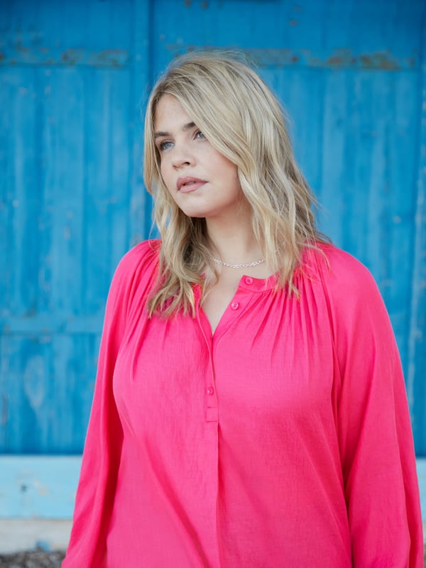 In striking pink, this blouse is cut from a soft chambray fabric thats so comfortable to wear. It has a round neckline with soft gathers, and a button-through front that creates a lengthening effect. Long raglan sleeves with elasticated cuffs add comfort and coverage, and complement its slightly swingy shape beautifully.