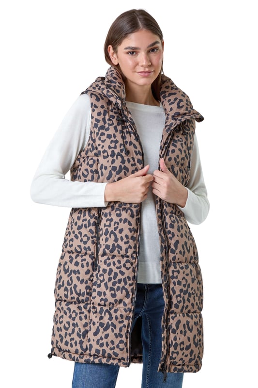 Animal Print Longline Hooded Gilet from Roman. Gilets are the perfect option for the transitional seasons, providing just the right amount of warmth for unpredictable weather. Cut from a woven fabric this gilet features a cosy funnel neck and a front zip fastening for a secure fit. A practical hood is finished with a drawstring cord for an adjustable fit, while zipped pockets provide space for your everyday essentials. Adorned in a fun animal print this piece is padded for extra warmth. Pair with relaxed denim and knitwear with either boots and trainers for trendy everyday style!