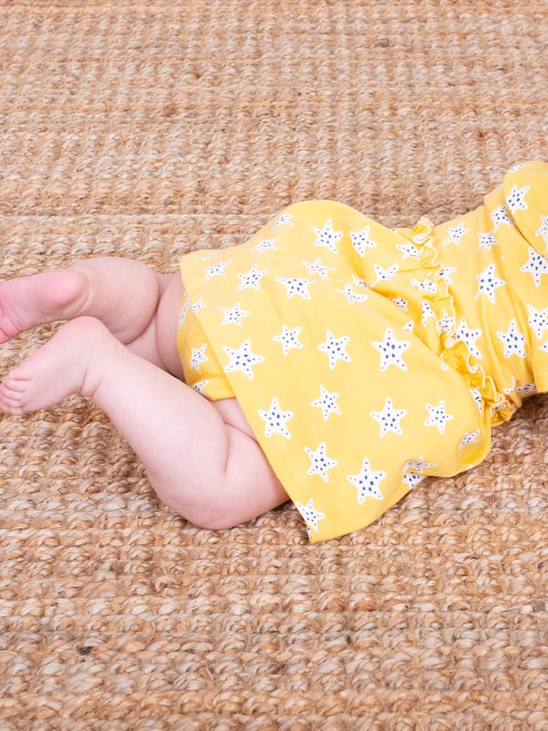 95% organic cotton 5% elastane | Proud to be certified to the Global Organic Textile Standard (GOTS) | Super starfish all-over print | Soft butter yellow | Single jersey with a little bit of stretch (180-190 gsm) | Combined bodysuit and dress | Popper crotch and shoulder opening | Short sleeved | Round neck | Made in Turkey | Machine washable at 40 degrees, or at 30 degrees to be kinder to the planet
