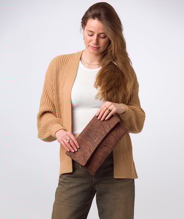 The 'Amelia' clutch bag from the Pure Luxuries Marylebone collection is handcrafted from high-quality, genuine Nappa leather with a natural super-soft touch. The fold-over top conceals a zip-top that opens to reveal the main compartment that is lined with 100% cotton. The fold-over top is secured by a magnetic press stud and features gold-coloured metal fittings and zip. The Pure Luxuries logo is embossed in gold foil for a beautifully simple finishing touch.