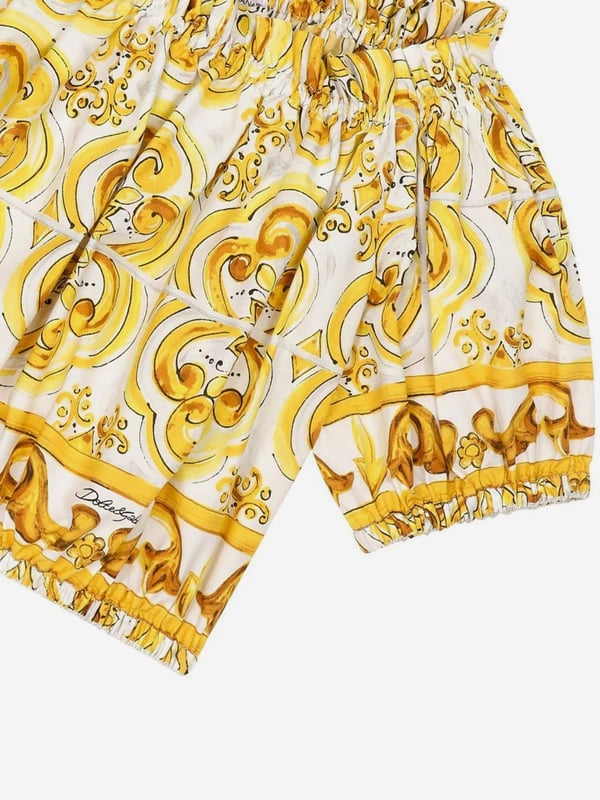 Dolce & Gabbana utilise new technological properties to create captivating aesthetics. This girls blouse is a part of the FW24/25 Girl‚  Collection. Depicted in Majolica, a symbol of Italian craftsmanship, it comes in lemon yellow, brightened up by pure white, taking inspiration from Sicilian pottery. Envisioned in cotton poplin with all-over yellow majolica print via a cropped fit and short puff sleeves, showcasing elasticated cuffs.  Made in Italy Boat Neck With Dropped Shoulders Stretch Hem Placed Print Due to "Handmade" Aspect 100% Cotton