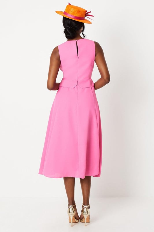 Elegant waistcoat-style bodice with button detailing
        Flattering V-neckline and sleeveless design
        Graceful midi length with a flowing drape skirt
        Sophisticated crepe fabric for a polished look
        Versatile silhouette suitable for various formal occasions
    
    Embody refined elegance with this captivating waistcoat midi dress. The structured bodice, adorned with delicate buttons, creates a striking contrast against the gracefully draped skirt, offering a harmonious blend of tailored sophistication and feminine fluidity. Perfect for weddings, race days, or any upscale event, this dress commands attention without compromising on comfort. Style it with strappy metallic heels and a coordinating fascinator for a quintessentially British look. For cooler evenings, drape a lightweight pashmina over your shoulders. Accessorise with understated jewellery to maintain the dress's clean lines and let its exquisite design take centre stage. This versatile piece transitions effortlessly from day to evening, making it a valuable addition to your occasion wear wardrobe.