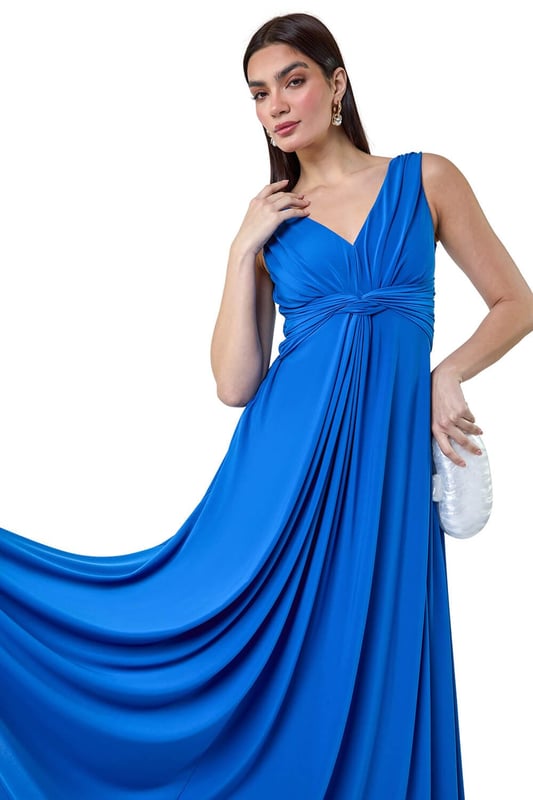 Plain Knot Front Maxi Dress from Roman. Turn heads in this luxuriously elegant knot front maxi dress. This exquisite sleeveless dress features a flattering v-neckline and a striking v-back detail, ensuring you make a sophisticated statement. With a fit and flare silhouette, this plain dress is fitted at the waist and flows into a floor-sweeping length, perfect for special occasions. The stretch jersey fabric drapes beautifully, while the knot detail at the waist adds an extra touch of glamour. Whether you're attending a wedding reception or a formal dinner, pair with strappy heels and a fascinator for a Summer wedding look.