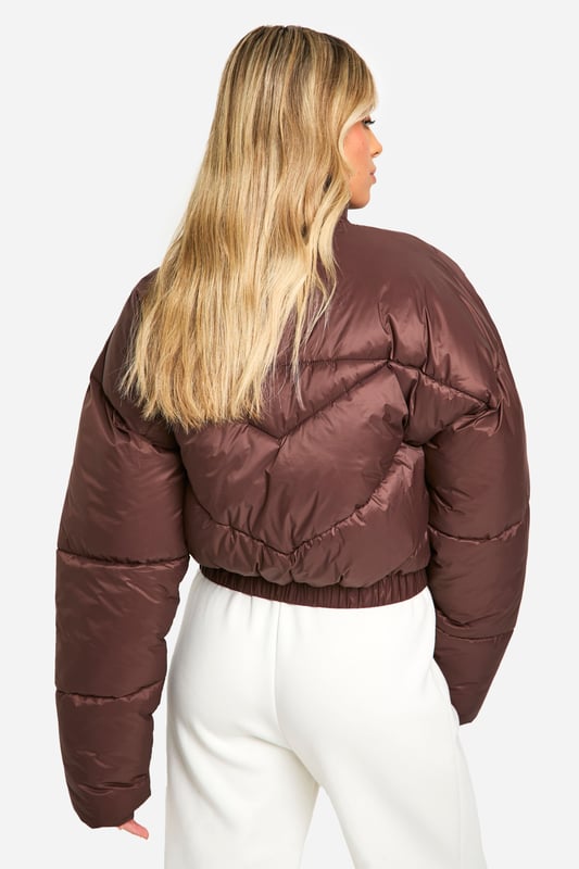 Quilted puffer jacket with funnel neck design
        Cropped length for a trendy silhouette
        Full-length zip closure for easy wear
        Chevron quilting pattern adds visual interest
        Ribbed cuffs for a snug fit and warmth retention
    
    Embrace the chilly weather in style with this eye-catching quilted puffer jacket. The funnel neck design not only adds a fashionable touch but also provides extra warmth on blustery days. Its cropped length makes it perfect for pairing with high-waisted trousers or skirts, creating a balanced and modern look. For a casual day out, team it with wide-leg trousers and trainers, as shown in the images. Add a baseball cap for an extra sporty vibe. This versatile piece is ideal for various casual occasions, from weekend brunches to shopping trips with friends. The chevron quilting pattern adds a subtle yet stylish detail, ensuring you stand out in the crowd. Whether you're heading to a family gathering or a casual meet-up, this jacket will keep you cosy without compromising on style.