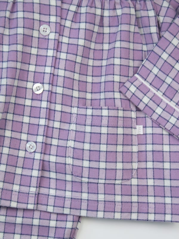 New for this Season...A great staple design for any girls pyjama drawer. Made in a beautiful soft brushed Cotton, this pyjama set has a small delicate check design using a Lavender Violet colour yarn with navy and ivory highlights. Always 'On Trend' and never out of fashion - they are Classic and Traditional in styling. Our signature design has white piping details around the collar and cuffs. With plenty of gathers, 2 patch pockets and engraved pearl effect buttons and your little one will be ready for the Autumn into winter.