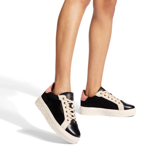 The Kensington Cupsole sneaker features a black suede leather upper with grey and pink panels. The front laces up with antiqued eagle head at the base of the laces. The sole is quilted in rubber.