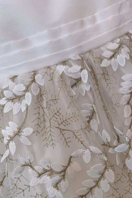 Another new style for us this year. We are so excited to have sourced the beautiful fabric for this style LUCY.

Fern style embroidered leaves in ivory, attached by gold thread stems. The gold catches in the light as the skirt moves and has a 3D effect which makes the leaves look realistic. A very distinctive fabric makes this girls special occasion dress quite unique. You won't see another dress like this on the high street!

The top of the dress is made using our 'Mock Silk' fabric and has a pin tucked sash that ties at the back in a big bow. It's fully lined in lightweight soft 100% cotton, just in case your little one has sentitive skin and also helps them not to get too sweaty after all the twirling and pirouetting around. Let's be honest ... all girls will feel like a princess in this!

All our dresses arrive with you on a satin padded hanger to help keep the dress in the best shape and then protected by one of our heritage garment keepsake bags
Outer - 100% Polyester
Lining - 100% Cotton
Dry Clean or Hand Wash only