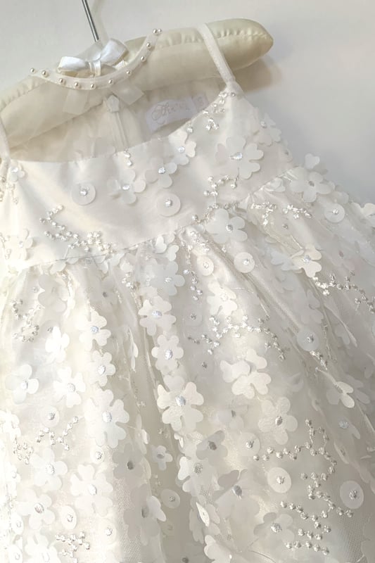 We always say 'it's in the detail' but it truly is with this style. The detail is in the amazing fabric! 3D Organza flowers attached with embroidered centres to Tulle.
We made the top of the dress in contrasting plain organza and finished it with pearl beads around the neck to give the impression of a necklace.
Suitable for baby and toddler girls, it is lined in 100% lighweight cotton lawn making it soft and comfy against your child's skin. Also good for girls with sensitive skin.
Style: KALI is ideal for Christenings, Baptisms, naming ceremonies, Flower girl or any other special occassion or family event!
Why not complete the look with one of our caridgans. Take a look at style VALENTINA. It too has pearls around the neck so would compliment this dress really well.
Finish off with a headband. LANA or MABEL would look equally beautiful.
All our dresses arrive with you on a Satin padded hanger, to help keep it's shape and protected by a Heritage garment keepsake bag.
Outer - 100% Polyester
lining - 100% cotton
Dry clean or Hand Wash