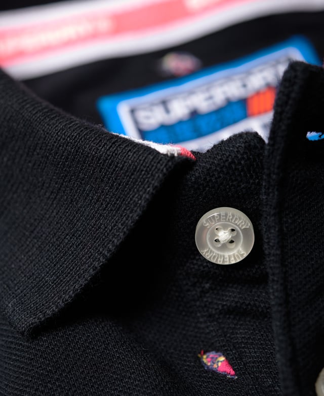 Superdry men's Bermuda polo shirt. This classic style polo shirt features short sleeves, two button fastening and an all over embroidered pattern. Finished with a Superdry logo tab on the hem and on one sleeve. Will look great with a pair of jeans or shorts and trainers this season.