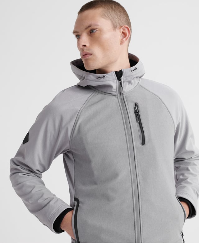 Superdry men's hooded Softshell jacket. Taking inspiration from hiking-wear, this softshell offers all the comfort of your favourite hoodie combined with the protection of a jacket. Featuring a practical hood with a bungee cord adjuster, full-length zip fastener, two front pockets with stormseal zip fastenings and reflective trims and a single zipped chest pocket with reflective trim. The hem has a bungee cord adjuster and the ribbed cuffs combine to keep you comfortable. Inside, the full fleece bonded lining forms two poacher style pockets for added practicality. The jacket is finished with Superdry branded zip pulls and a logo patch on the right sleeve.