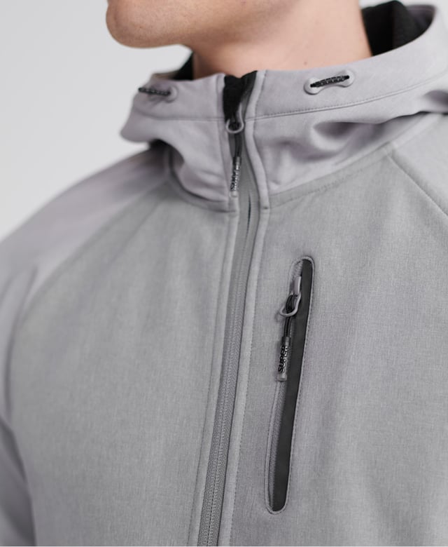 Superdry men's hooded Softshell jacket. Taking inspiration from hiking-wear, this softshell offers all the comfort of your favourite hoodie combined with the protection of a jacket. Featuring a practical hood with a bungee cord adjuster, full-length zip fastener, two front pockets with stormseal zip fastenings and reflective trims and a single zipped chest pocket with reflective trim. The hem has a bungee cord adjuster and the ribbed cuffs combine to keep you comfortable. Inside, the full fleece bonded lining forms two poacher style pockets for added practicality. The jacket is finished with Superdry branded zip pulls and a logo patch on the right sleeve.