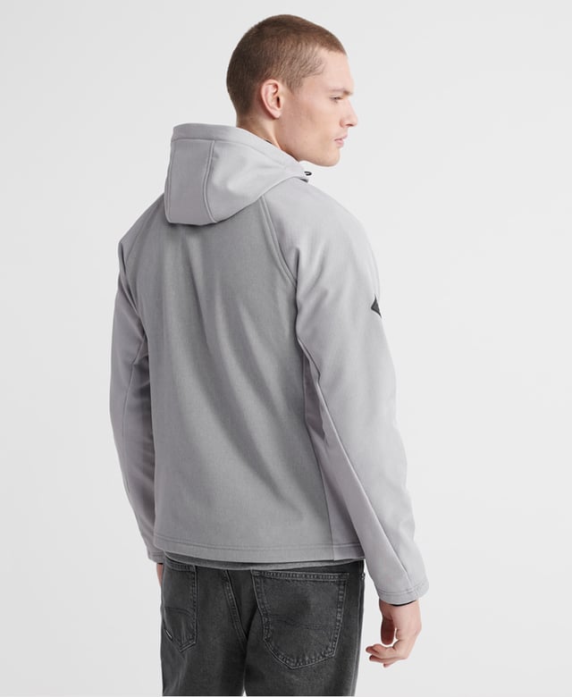 Superdry men's hooded Softshell jacket. Taking inspiration from hiking-wear, this softshell offers all the comfort of your favourite hoodie combined with the protection of a jacket. Featuring a practical hood with a bungee cord adjuster, full-length zip fastener, two front pockets with stormseal zip fastenings and reflective trims and a single zipped chest pocket with reflective trim. The hem has a bungee cord adjuster and the ribbed cuffs combine to keep you comfortable. Inside, the full fleece bonded lining forms two poacher style pockets for added practicality. The jacket is finished with Superdry branded zip pulls and a logo patch on the right sleeve.