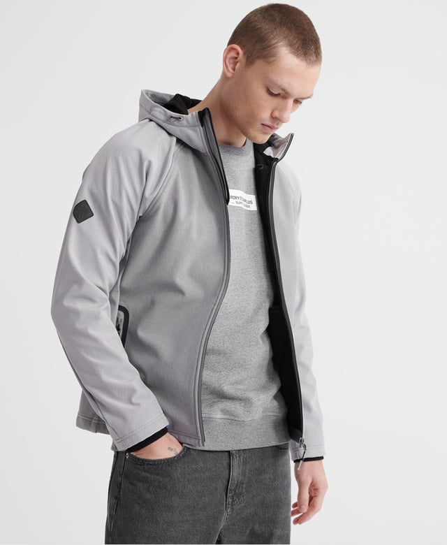 Superdry men's hooded Softshell jacket. Taking inspiration from hiking-wear, this softshell offers all the comfort of your favourite hoodie combined with the protection of a jacket. Featuring a practical hood with a bungee cord adjuster, full-length zip fastener, two front pockets with stormseal zip fastenings and reflective trims and a single zipped chest pocket with reflective trim. The hem has a bungee cord adjuster and the ribbed cuffs combine to keep you comfortable. Inside, the full fleece bonded lining forms two poacher style pockets for added practicality. The jacket is finished with Superdry branded zip pulls and a logo patch on the right sleeve.
