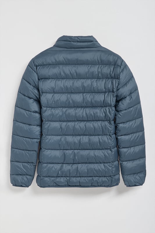 Unsere Ultralight-Herrenjacke Chase zeichnet sich durch ein modernes und funktionelles Design aus. Die leichte Steppung wärmt, ohne den Komfort zu beeinträchtigen. Sie ist ohne Kapuze und mit Reißverschluss ausgestattet und verfügt über zwei Seitentaschen und eine Innentasche mit Reißverschluss für zusätzliche Funktionalität. Das Kleidungsstück ist wasserabweisend, jedoch nicht völlig wasserdicht, was es zu einer perfekten Wahl für eine Vielzahl von Wetterbedingungen macht. Unser neuer gummierter, farblich angepasster Rigby Go Aufnäher auf der Brust, die schrägen Einsätze und das Futter in Kontrastfarbe machen dieses Kleidungsstück zu einem modernen Klassiker.