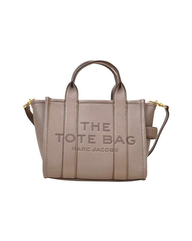 The iconic Tote Bag from Marc Jacobs comes in a cool, elegant mini version for this season. It comes in black leather with "The Tote Bag" inscribed on the front, and is the statement piece you need for an effortless summer wardrobe. Wear it with a floaty, print dress to contrast with its pared-down style! Shoulder strap : 69 cm - Top handle : 11 cm. Worn two ways - two top handles and one adjustable detachable shoulder strap. Material : cowskin. Lining : leather. Colour : Gris - Cement. Handle drop : 69 cm. Closure :  Top zip. Interior: no pockets. MINI TOTE becomes SMALL TOTE. width: 130mm, length: 260mm, height: 210mm
