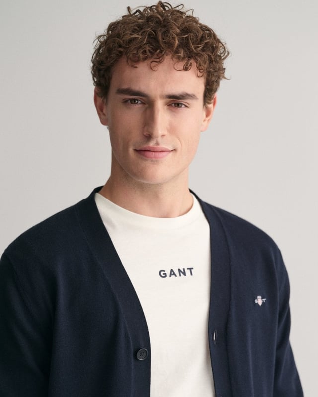 This durable and sophisticated cardigan from GANT is crafted in 100% cotton. Cut for a regular fit, it features a V-neck, knitted pockets, branded corozo buttons and ribbed detailing at the hem and cuffs. This piece is accented with a GANT shield graphic embroidered at the chest. 

Regular fit
V-neck
Knitted pockets
Rib detailing at hem and cuffs
GANT graphic embroidered at chest

100% cotton
8030556
 