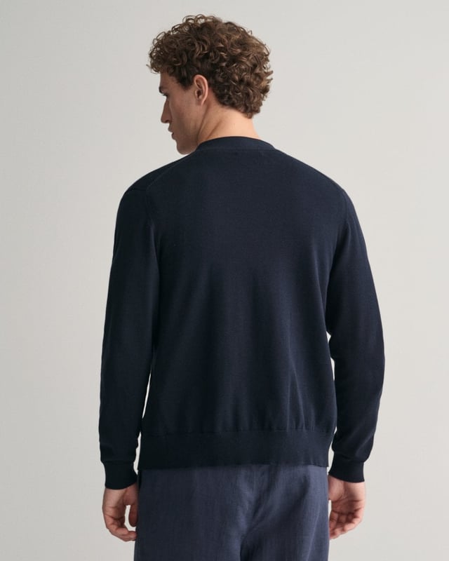 This durable and sophisticated cardigan from GANT is crafted in 100% cotton. Cut for a regular fit, it features a V-neck, knitted pockets, branded corozo buttons and ribbed detailing at the hem and cuffs. This piece is accented with a GANT shield graphic embroidered at the chest. 

Regular fit
V-neck
Knitted pockets
Rib detailing at hem and cuffs
GANT graphic embroidered at chest

100% cotton
8030556
 