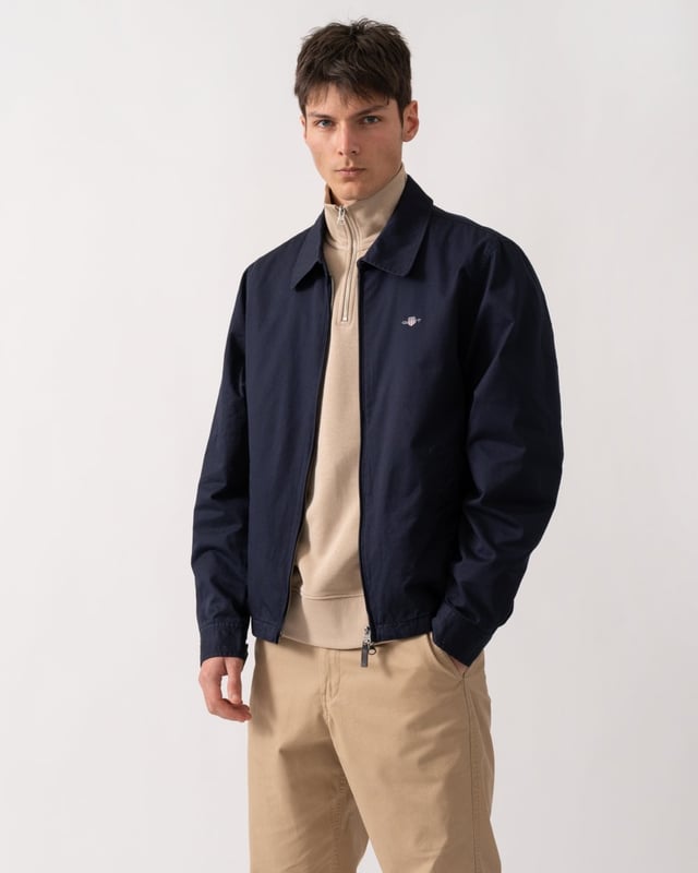 This jacket takes inspiration from GANT's beloved windcheater design, incorporating updated elements for the new season. Crafted from a water-repellent cotton twill shell, it is half-lined to shield against the cold while ensuring breathability. Designed for a regular fit that sits just above the hips, it features a partly elasticated hem for added comfort. Additional details include a front zip closure with a leather extender, slanted side welt pockets with hidden press buttons, two interior jetted pockets, and buttoned cuffs. It is finished with logo embroidery at the chest and a signature branded locker loop at the back. 

Regular fit
Above hip length
Water-repellent (DWR treatment)
Two outer and inner pockets

Shell - 100% Cotton, Upper Back Lining - 100% Cotton, Sleeve Lining - 100% Recycled Polyester 
7006494