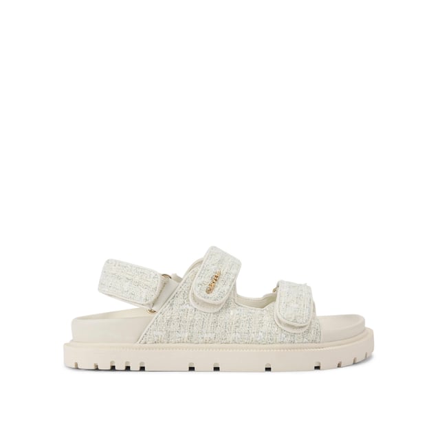 The Carvela Rosa Sandal is crafted in a cream tweed fabric. There is overstitch quilting in a diamond style across the upper straps. There is a gold branding detail on the top strap.