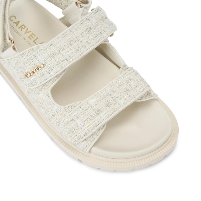 The Carvela Rosa Sandal is crafted in a cream tweed fabric. There is overstitch quilting in a diamond style across the upper straps. There is a gold branding detail on the top strap.