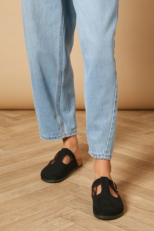 T-bar design for a classic Mary Jane silhouette
        Closed toe for added protection and versatility
        Comfortable footbed for all-day wear
        Faux suede upper for a luxurious look and feel
        Flat heel between 0 and 2cm for easy walking
    
    Step into effortless style with these Emmeline faux suede mules from Oasis. The T-bar Mary Jane design offers a charming nod to vintage aesthetics while maintaining a contemporary edge. Perfect for daywear, these versatile flats can take you from casual brunches to family gatherings with ease. Pair them with cropped jeans and a crisp white tee for a laid-back weekend look, or style them with a flowy midi dress for a more polished ensemble. The closed toe and comfortable footbed ensure all-day comfort, making these mules ideal for city exploring or leisurely strolls in the park. Their flat heel provides stability without sacrificing style, allowing you to navigate your day with confidence and grace.
