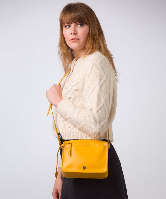 The 'Aurora' cross body bag from Conkca London elevates this classic design with a natural leather exterior for a beautifully smooth finish. A zip-over top conceals the central 100% cotton lined compartment alongside a handy slip pocket. Additional storage space is provided by a zipped pocket and slip pocket, ideal for on-the-go storage. The accessory comes with an adjutable leather strap secured with rustic gold metal fittings; this is all finished with the iconic Conkca London logo and charm.