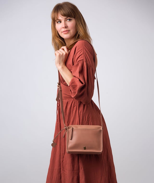 The 'Aurora' cross body bag from Conkca London elevates this classic design with a natural leather exterior for a beautifully smooth finish. A zip-over top conceals the central 100% cotton lined compartment alongside a handy slip pocket. Additional storage space is provided by a zipped pocket and slip pocket, ideal for on-the-go storage. The accessory comes with an adjutable leather strap secured with rustic gold metal fittings; this is all finished with the iconic Conkca London logo and charm.