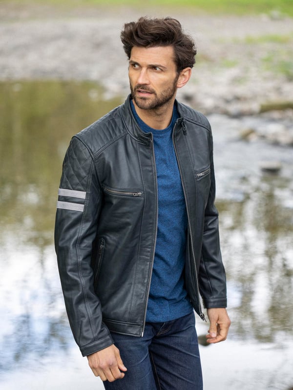 With all the hallmarks of a Lakeland favourite jacket, Charlie is a contemporary update to a traditional cafe racer design.
A slim fit biker inspired jacket with a cafe racer classic silhouette, buckle press stud collar, press stud cuffs and side fastening and contrasting stripe. For fans of the motorcycle era this jacket gives a nod to the racing heritage. The striking navy design with quilted shoulder stitching and coloured leather stripes on the sleeve is crafted from UK sourced aniline leather for a soft sheen. The Charlie biker is a garment that will age beautifully the more you wear it, creating a fit unique to the wearer.