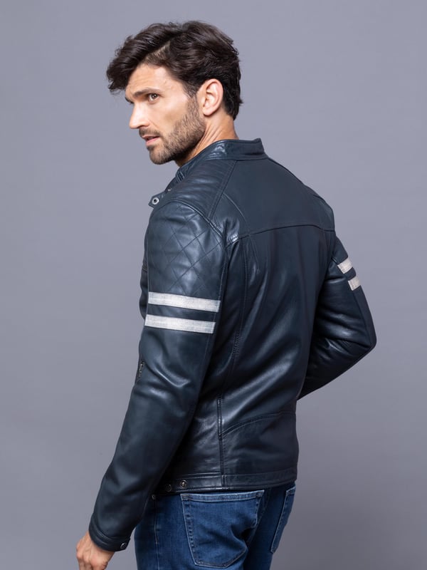 With all the hallmarks of a Lakeland favourite jacket, Charlie is a contemporary update to a traditional cafe racer design.
A slim fit biker inspired jacket with a cafe racer classic silhouette, buckle press stud collar, press stud cuffs and side fastening and contrasting stripe. For fans of the motorcycle era this jacket gives a nod to the racing heritage. The striking navy design with quilted shoulder stitching and coloured leather stripes on the sleeve is crafted from UK sourced aniline leather for a soft sheen. The Charlie biker is a garment that will age beautifully the more you wear it, creating a fit unique to the wearer.